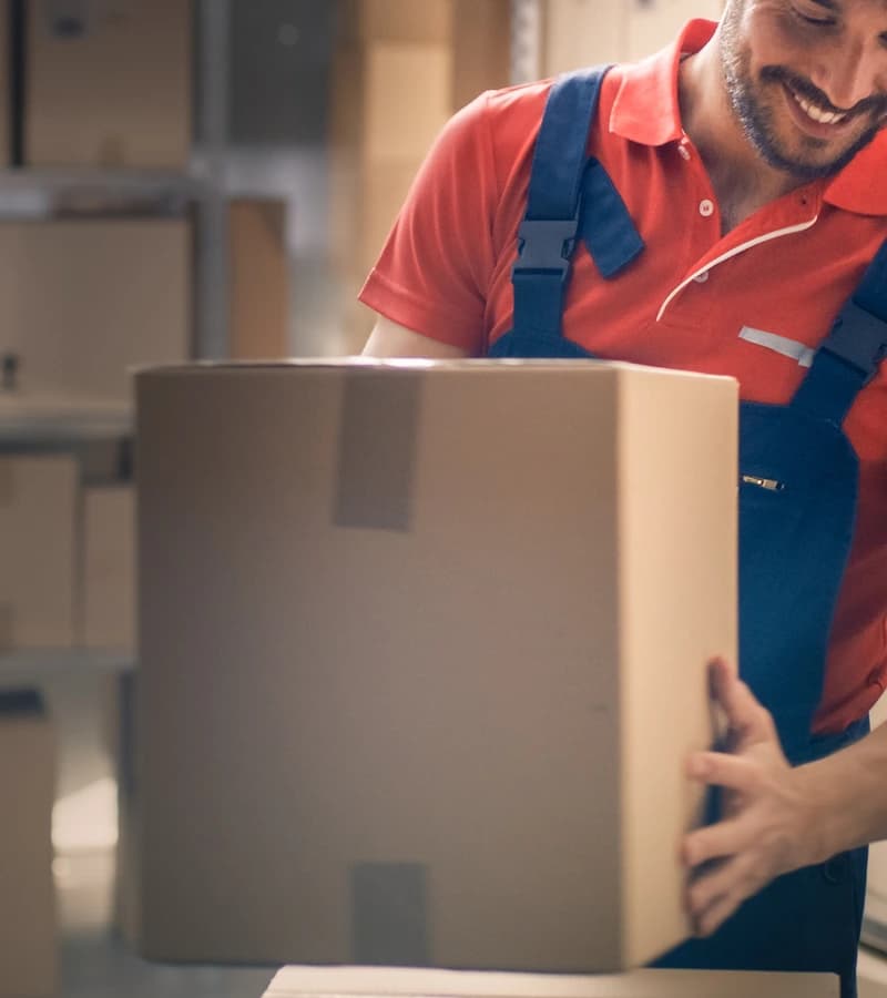 Warehouse worker in red uniform handling packages representing white glove and 3PL final mile delivery