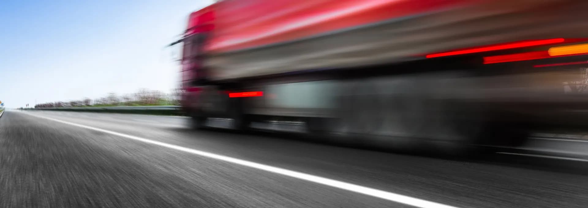 Red freight truck moving at speed on a highway for hot shot trucking